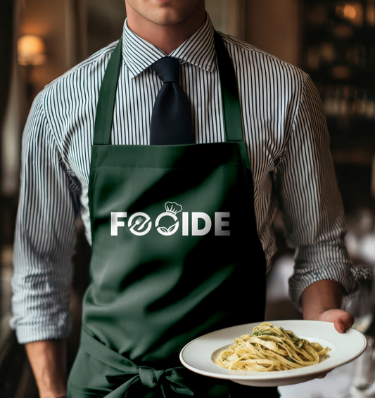Person wearing a green apron with 'FOOIDE' logo, holding a plate of pasta.